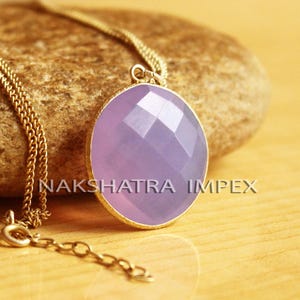 May include: A gold chain necklace with a lavender oval pendant. The pendant has a faceted design.