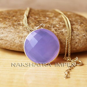 May include: A delicate gold chain necklace with a round, faceted lavender chalcedony pendant. The pendant is approximately 1 inch in diameter.