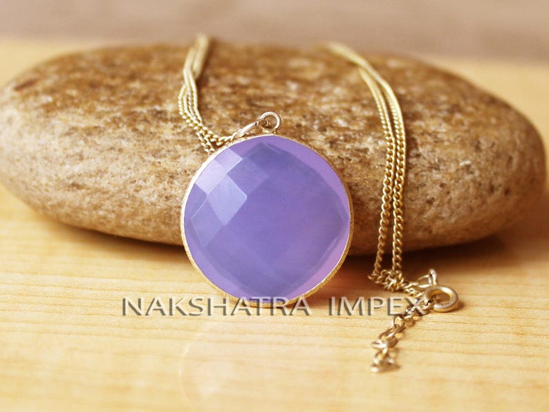 May include: A delicate gold chain necklace with a round, faceted lavender chalcedony pendant. The pendant is approximately 1 inch in diameter.