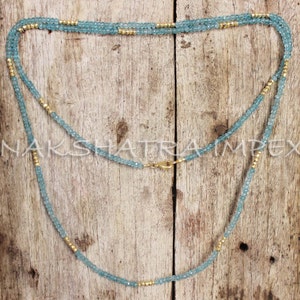 Puede incluir: Un collar largo hecho de cuentas de color azul claro y dorado. El collar est&aacute; en capas y tiene un cierre de broche.