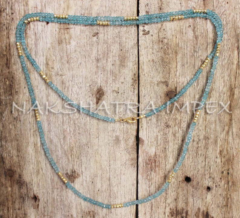 Puede incluir: Un collar largo hecho de cuentas de color azul claro y dorado. El collar est&aacute; en capas y tiene un cierre de broche.