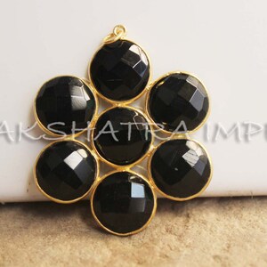 May include: Gold pendant featuring seven black faceted gemstones arranged in a flower design.