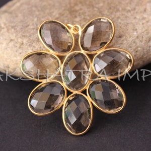 May include: A gold-toned pendant featuring a flower design with eight faceted smoky quartz stones.