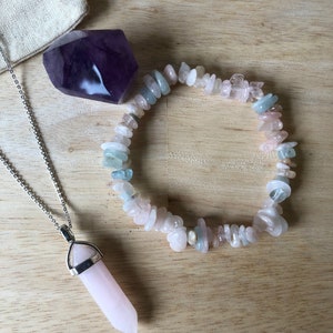 May include: A set of three crystal stones, including a purple amethyst, a pink rose quartz, and a bracelet made of light pink, blue, and white stones.