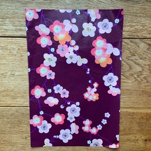 May include: Purple wrapping paper with a white and pink floral pattern. The flowers are stylized and resemble cherry blossoms.