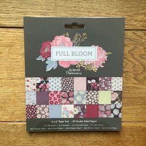 Könnte beinhalten: Ein Pack mit 50 doppelseitigen 15,24 x 15,24 cm großen Papierbögen mit floralen Designs in Rosa-, Rot- und Blautönen. Das Pack heißt "Full Bloom" von decraft's Papermania.