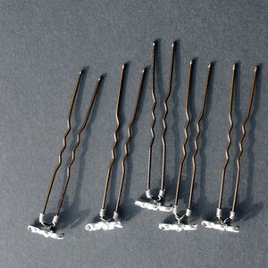 May include: Seven brown bobby pins with silver-colored ends. The bobby pins have a wavy design.