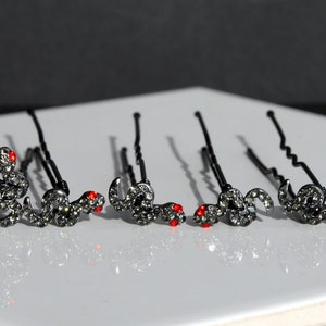 May include: Set of six black hair clips with a rhinestone snake design. Each snake has red eyes.