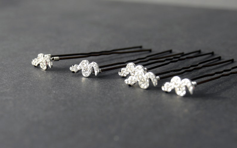 May include: Set of six black hair pins with silver rhinestone accents in the shape of a wavy line.