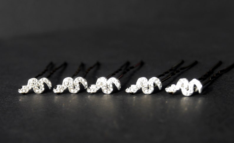 May include: Six silver hair clips with a wavy design adorned with clear rhinestones.