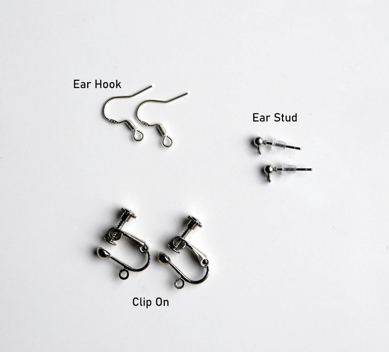 May include: Three different types of earring findings: ear hooks, ear studs, and clip-on earrings. All findings are silver in color.