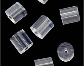 May include: A selection of clear, cylindrical earring backs with a central hole, set against a black backdrop. The earring backs are made of a transparent material, allowing light to pass through. The shapes vary slightly, with some appearing more rectangular.