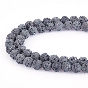 May include: A strand of dark grey lava rock beads. The beads are round and have a rough, textured surface.