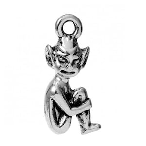 May include: A silver-toned pendant depicting a seated goblin or imp. The figure has pointed ears and is clutching its knees. The pendant has a loop at the top for attaching to a chain. The pendant is approximately 3 cm in height.