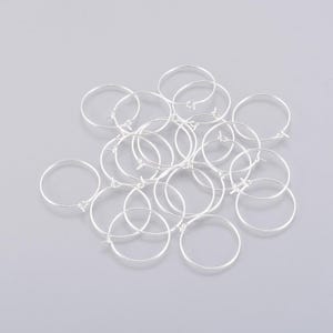 May include: A pile of silver hoop earrings. The hoops are all the same size and are made of a thin metal.
