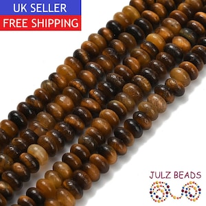 May include: Three parallel strands of round, flat-edged tiger's eye gemstone beads. The beads feature natural variations in golden-brown, amber, and dark brown tones with a polished, reflective finish. The text JULZ BEADS is visible in the corner.