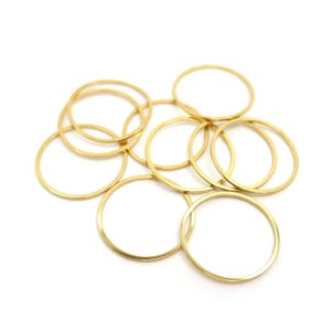 May include: A group of ten gold-coloured metal rings, all of the same size and shape, are piled on top of each other. The rings are smooth and shiny.