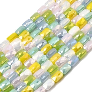 May include: Close-up of a strand of colourful, faceted beads. The beads are rectangular and feature a mix of pastel colours, including yellow, green, blue, and white. The beads are arranged in a neat, organised pattern.