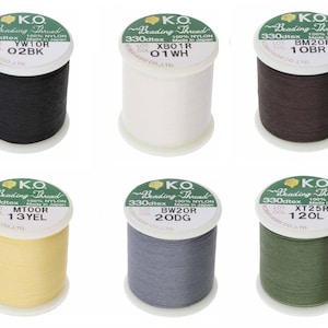May include: A selection of six K.O. Beading Thread spools in shades like black, white, brown, yellow, grey, and green. Each spool displays the thread's colour code and details, such as 330dtex and 100% nylon.