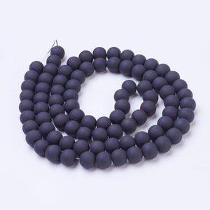 May include: A strand of dark grey matte round beads. The beads are strung on a clear thread.