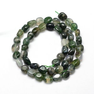 May include: A strand of green moss agate beads. The beads are smooth and polished, with a natural, irregular shape. They are a light green colour with darker green and white markings.