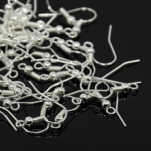 May include: A collection of silver-toned metal earring hooks featuring a curved wire design, a small decorative coil, and a spherical bead accent. Each hook includes a small circular loop at the bottom for attaching jewellery components.