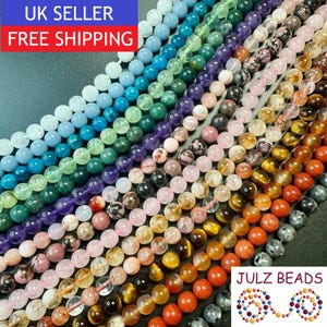 May include: A collection of round, polished gemstone beads arranged in parallel diagonal rows. The beads display a spectrum of colours including light blue, green, purple, pink, clear, yellow, brown, orange, and grey, featuring varied textures.
