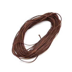 May include: A spool of brown cord or twine. The cord is tightly wound and appears to be made of natural fibres.