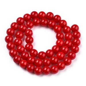 May include: A strand of bright red round beads made of coral. The beads are smooth and polished, and they are strung together on a clear thread.