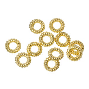 May include: A group of ten gold-coloured metal jump rings. The rings are all the same size and have a slightly textured surface.