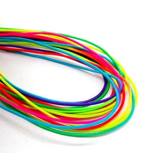 May include: A collection of colourful elastic cords in various bright colours, including yellow, green, blue, pink, and red. The cords are arranged in a loose circle, creating a rainbow effect.