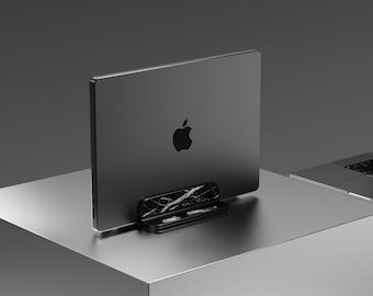 May include: A black laptop computer is raised on a black stand. The laptop is closed and has an Apple logo on the back. The laptop is on a gray surface.