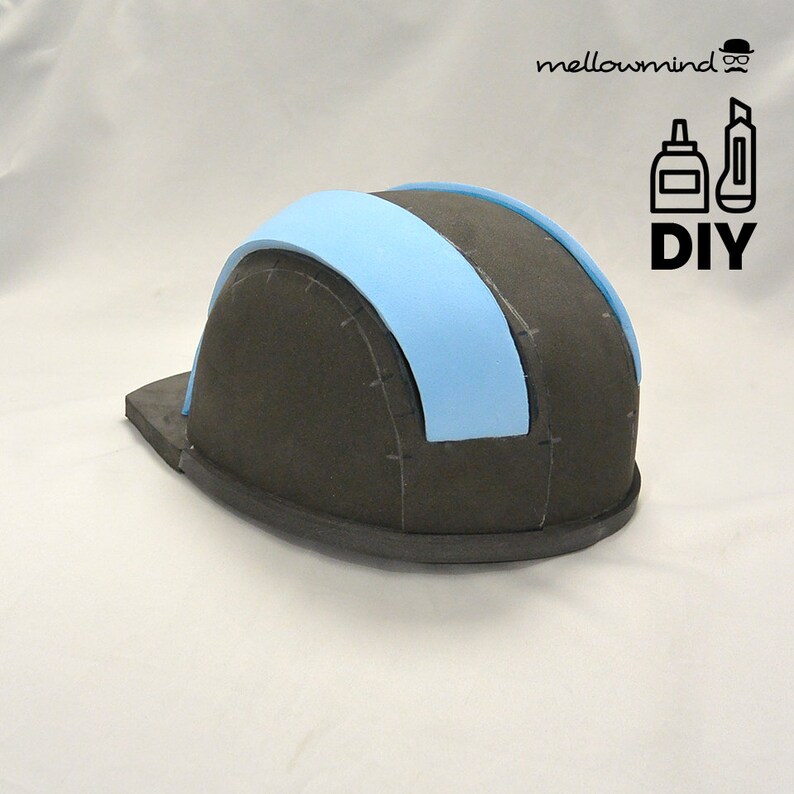 Op de afbeelding: Een doe-het-zelf project met een gedeeltelijk geconstrueerde helm van donkergrijs schuim met lichtblauwe accenten. De helm heeft een rand en een gebogen bovenstuk. De tekst "DIY" en het logo "mellowmind" zijn inbegrepen.