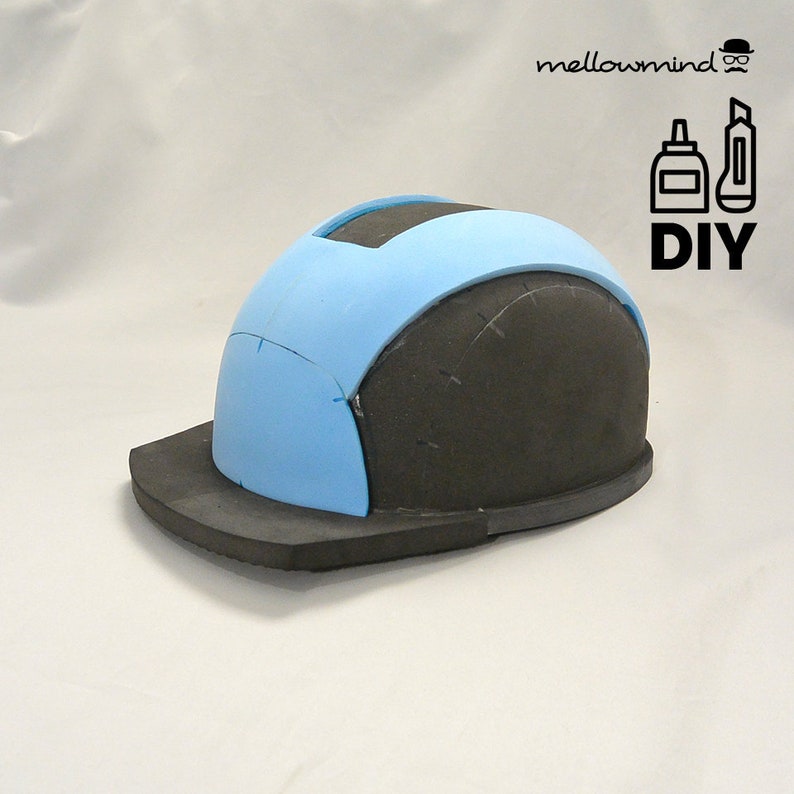 Op de afbeelding: Een doe-het-zelf project met een gedeeltelijk geassembleerde helm van zwart en lichtblauw schuim. De helm heeft een vizier en een gebogen bovendeel. De afbeelding bevat de tekst "DIY" en het logo "mellowmind".
