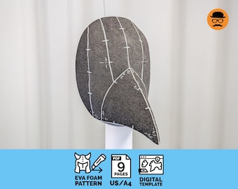 May include: A dark gray textured mask with a pointed beak-like protrusion, featuring white hand-drawn guide lines and markings. Below the mask, icons indicate a 9-page PDF digital template for an EVA foam pattern in US and A4 paper sizes.