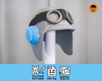 May include: A gray and black aviator helmet made of EVA foam, featuring large goggles and a blue side piece. The helmet is displayed on a white stand. The image includes text that says "EVA FOAM PATTERN", "12 PAGES", and "DIGITAL TEMPLATE".