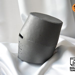 May include: A gray, cylindrical helmet with a cross design and eye slit. The helmet is angled and appears to be made of a textured material. The words "DIGITAL TEMPLATE" are visible in the lower right corner.