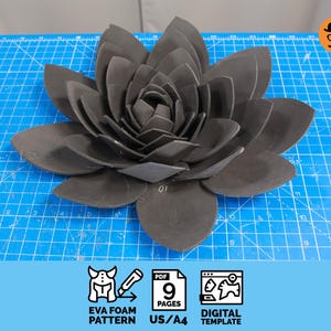 May include: A large, dark gray EVA foam flower, meticulously crafted with layered petals. The flower is centered on a blue cutting mat. The image includes icons indicating a digital template, EVA foam pattern, and 9 pages, US/A4.