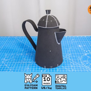以下が含まれることがあります： 黒いEVAフォームのコーヒーポットのパターン。パターンは組み立てられ、青いグリッドの表面に表示されます。画像には、EVAフォームパターン、10ページ、デジタルテンプレートのアイコンが含まれています。