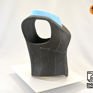 May include: A black foam vest with a light blue foam collar. The vest has markings for sewing and is on a white surface.