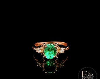 Anillo de oro rosa de 9 quilates con diseño de esmeralda cultivada en laboratorio y montura retorcida.