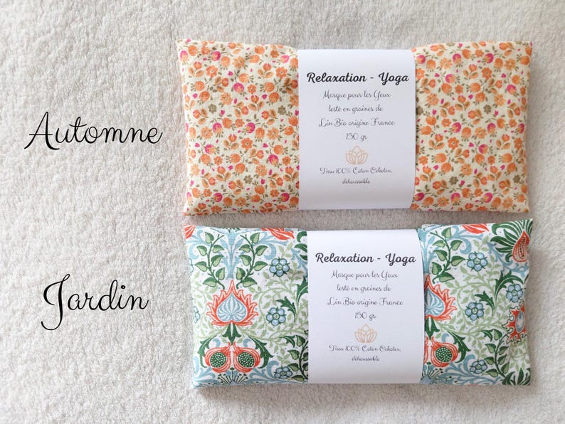 May include: Two rectangular eye pillows with white paper bands. The top pillow features an orange and pink floral pattern labeled Automne. The bottom pillow has a blue, green, and orange botanical print labeled Jardin. Both include French text.