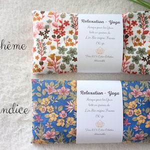 May include: Two rectangular eye pillows with floral patterns. The top pillow has a white background with red, orange, and green flowers. The bottom pillow has a blue background with yellow and pink flowers. Each has a white label reading Relaxation - Yoga.