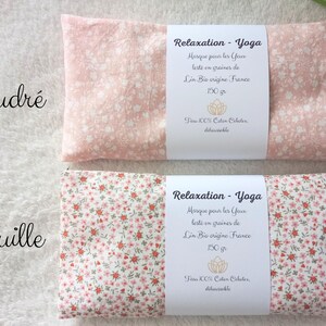 May include: Two rectangular eye masks with floral patterns. The top mask is light pink with white flowers, labeled Poudr&eacute;. The bottom mask has a dense red and green floral print, labeled Rouille. Both feature white paper bands with French text.