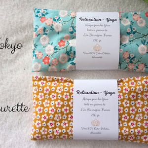 May include: Two rectangular eye pillows with fabric covers. The top pillow is light blue with a pink and white floral pattern labeled Tokyo. The bottom pillow is mustard yellow with a small white and red floral pattern labeled Fleurette.