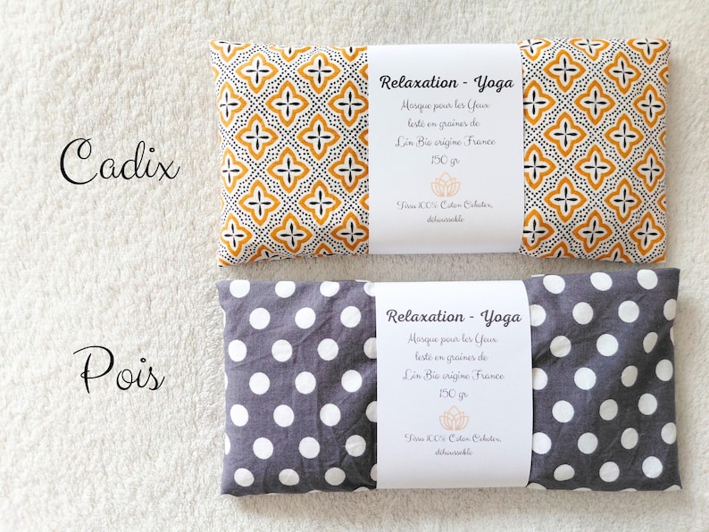 May include: Two rectangular eye pillows with white paper bands. The top pillow features a yellow and black geometric pattern labeled Cadix. The bottom pillow has a gray and white polka dot pattern labeled Pois. Both bands state Relaxation - Yoga, 150 gr.