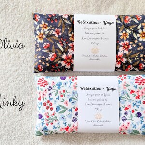 May include: Two rectangular eye pillows with floral patterns. The top pillow has a dark gray background with red and white flowers. The bottom pillow has a white background with blue, pink, and purple flowers. Each has a white label reading Relaxation - Yoga.