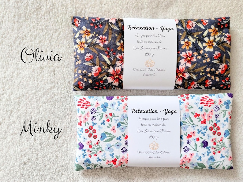 May include: Two rectangular eye pillows with floral patterns. The top pillow has a dark gray background with red and white flowers. The bottom pillow has a white background with blue, pink, and purple flowers. Each has a white label reading Relaxation - Yoga.