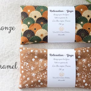 May include: Two rectangular eye masks labeled Relaxation-Yoga. The top mask features a bronze, green, and cream fan pattern. The bottom mask is caramel with a white floral print. Each has a white paper band stating 150g and 100% cotton.