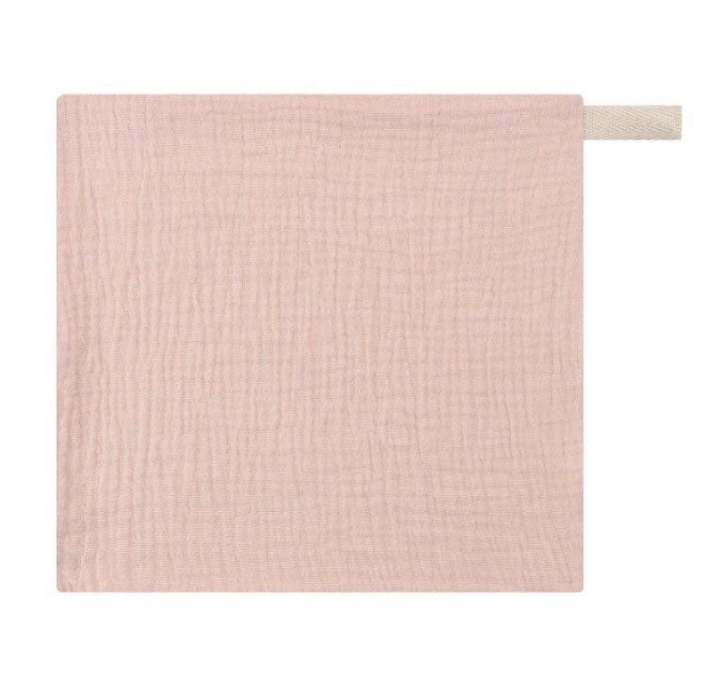 Pu&ograve; includere: Un quadrato di tessuto di mussola rosa pallido con un anello di tessuto bianco attaccato a un angolo.